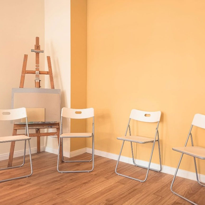 Stuhlkreis mit Staffelei im Hintergrund